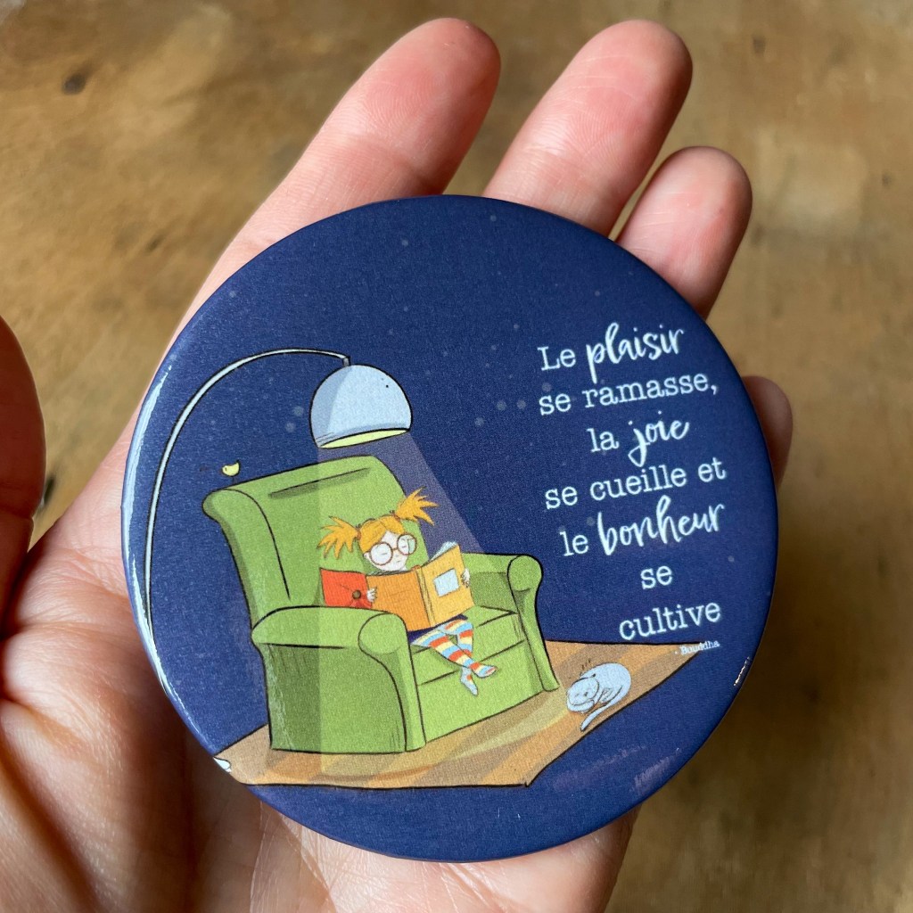 Aimant rond 3 pouces avec le dessin d'une fillette qui lit assise dans une fauteuil et l'inscription:"Le plaisir sur ramasse, la joie se cueille et le bonheur se cultive".